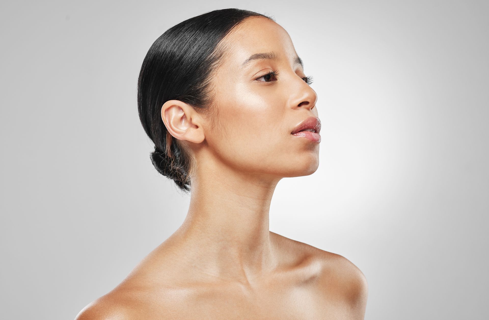A close up of a woman 's face with her hair in a bun.