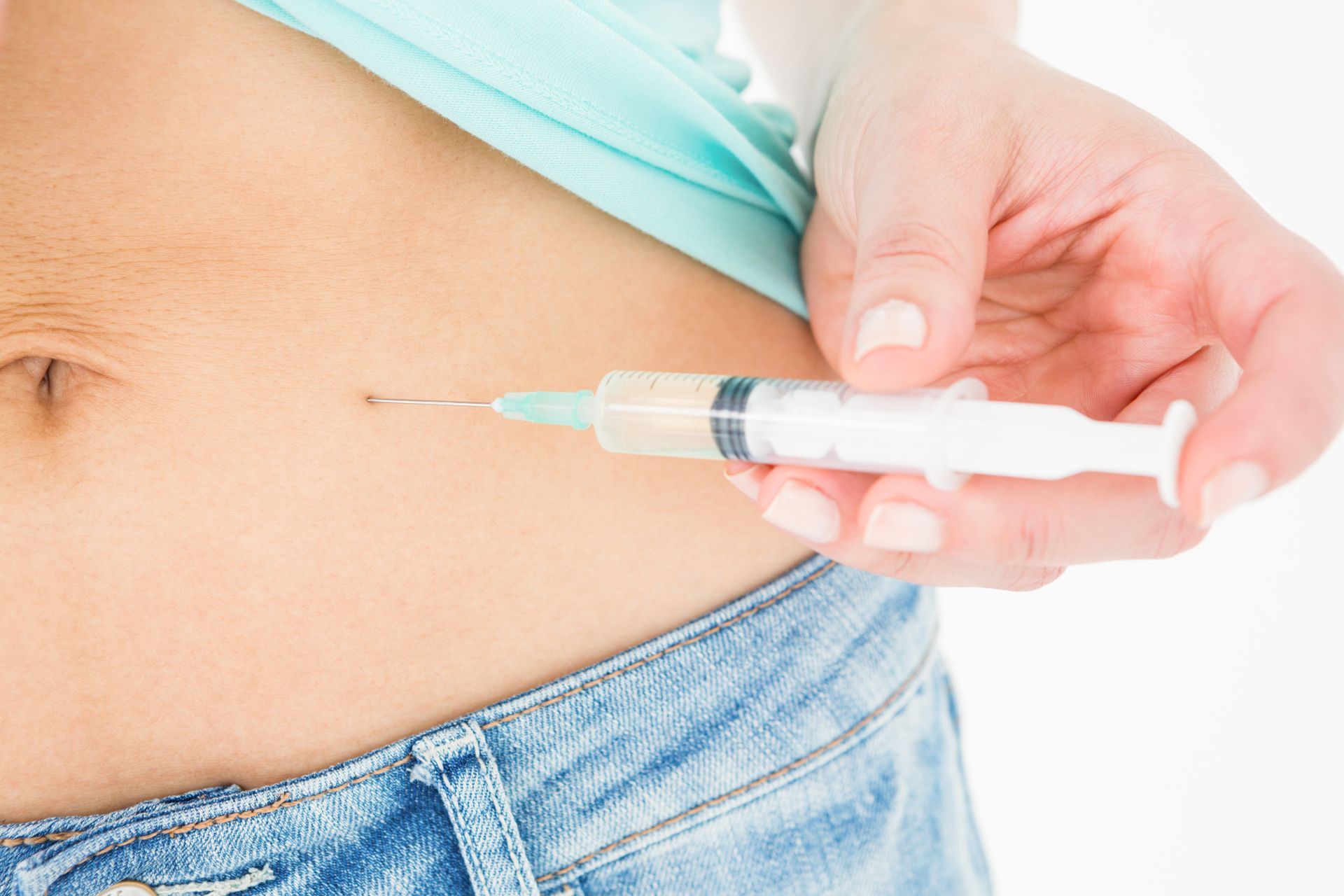 A woman is holding a syringe in her stomach.