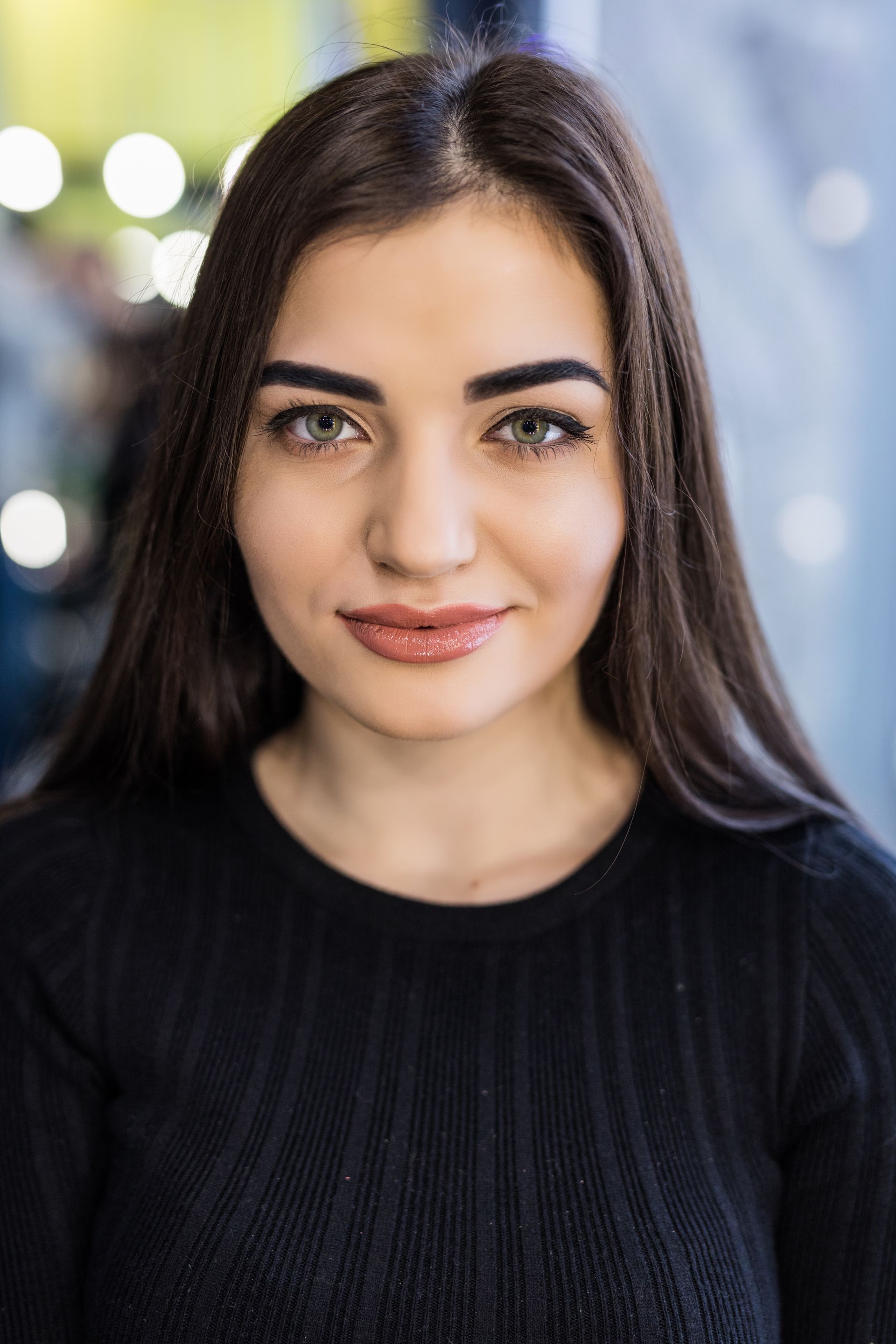 The woman is wearing a black sweater and looking at the camera.