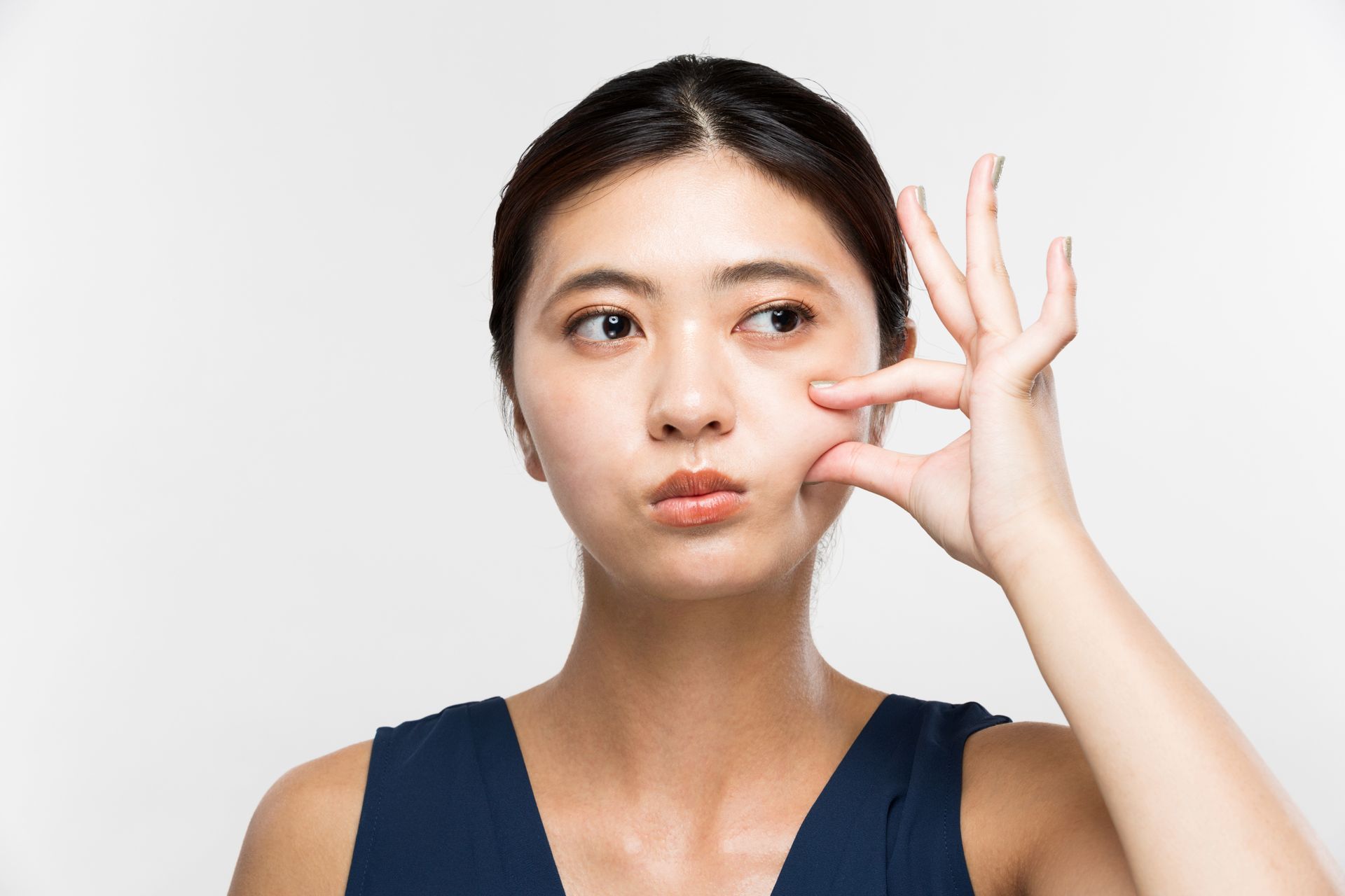 Woman with pursed lips, pinching skin on her face, looking concerned.