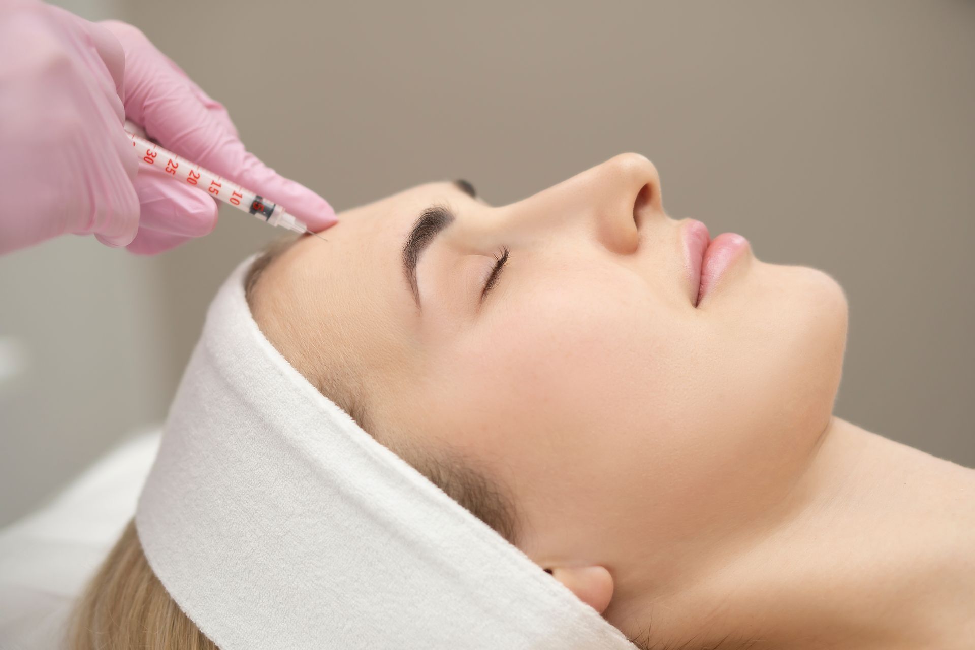 A woman is getting a botox injection in her forehead.