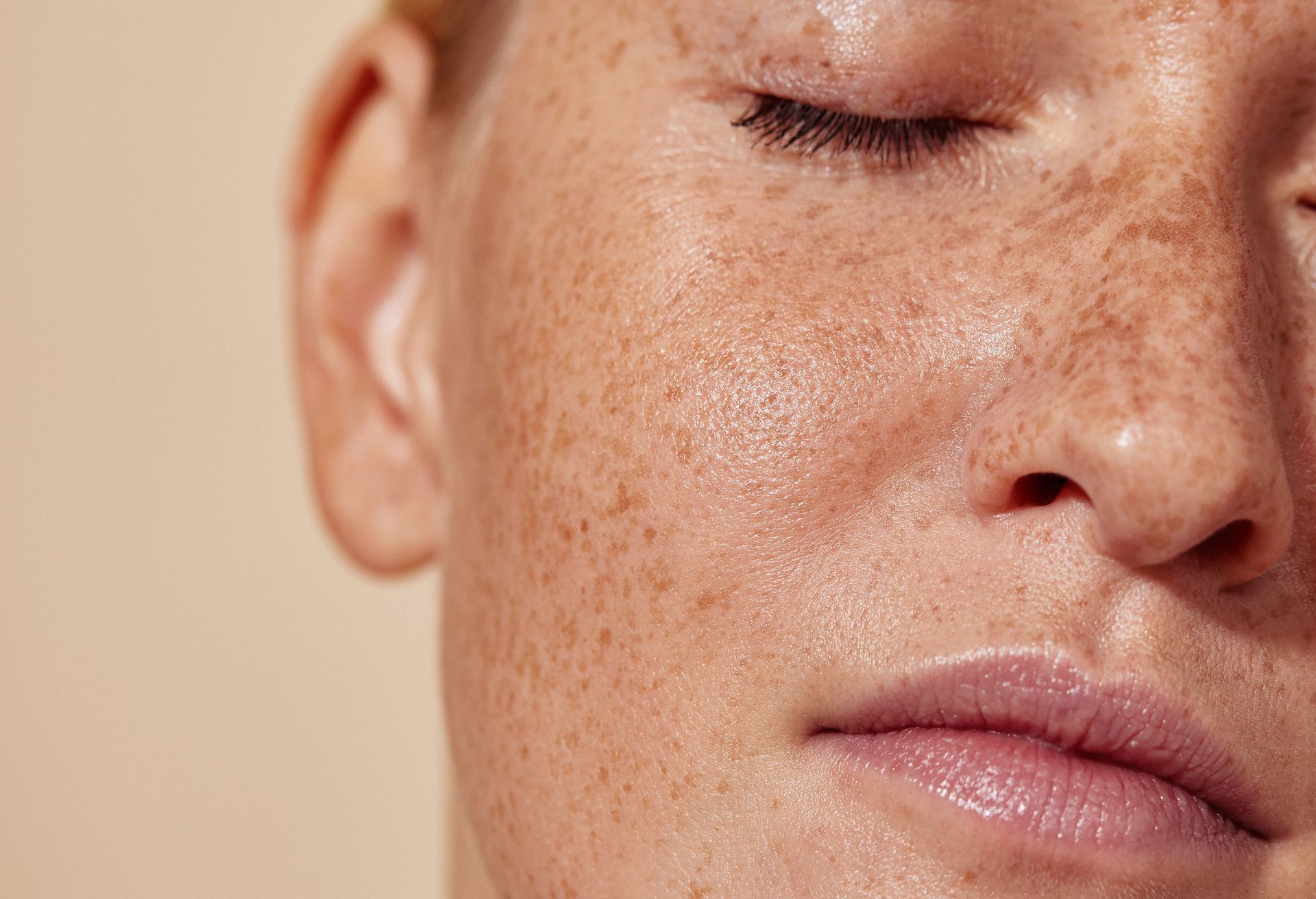 A close up of a woman 's face with freckles and her eyes closed.