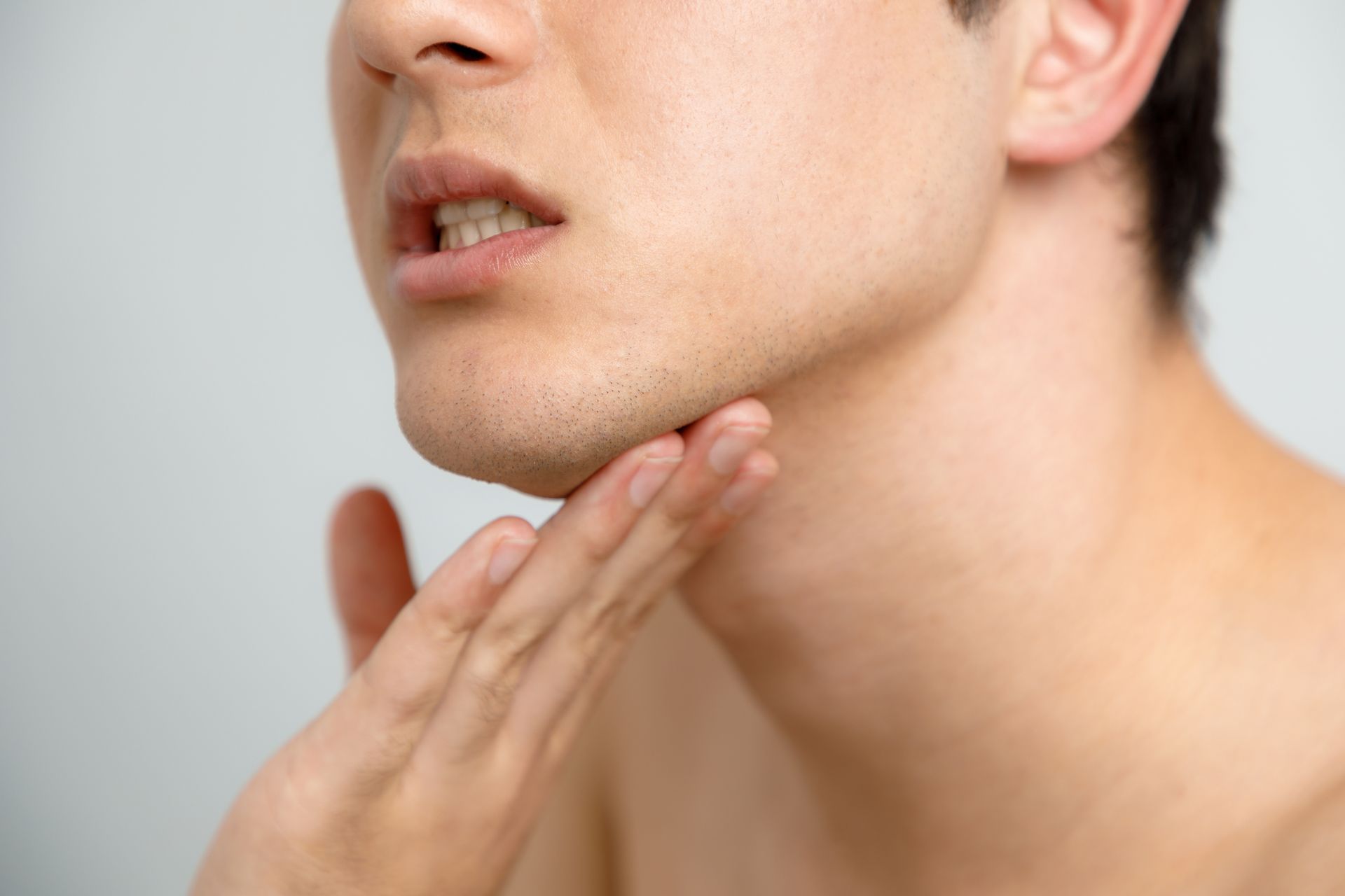 Close-up of a person's neck and chin, hand touching the jawline.