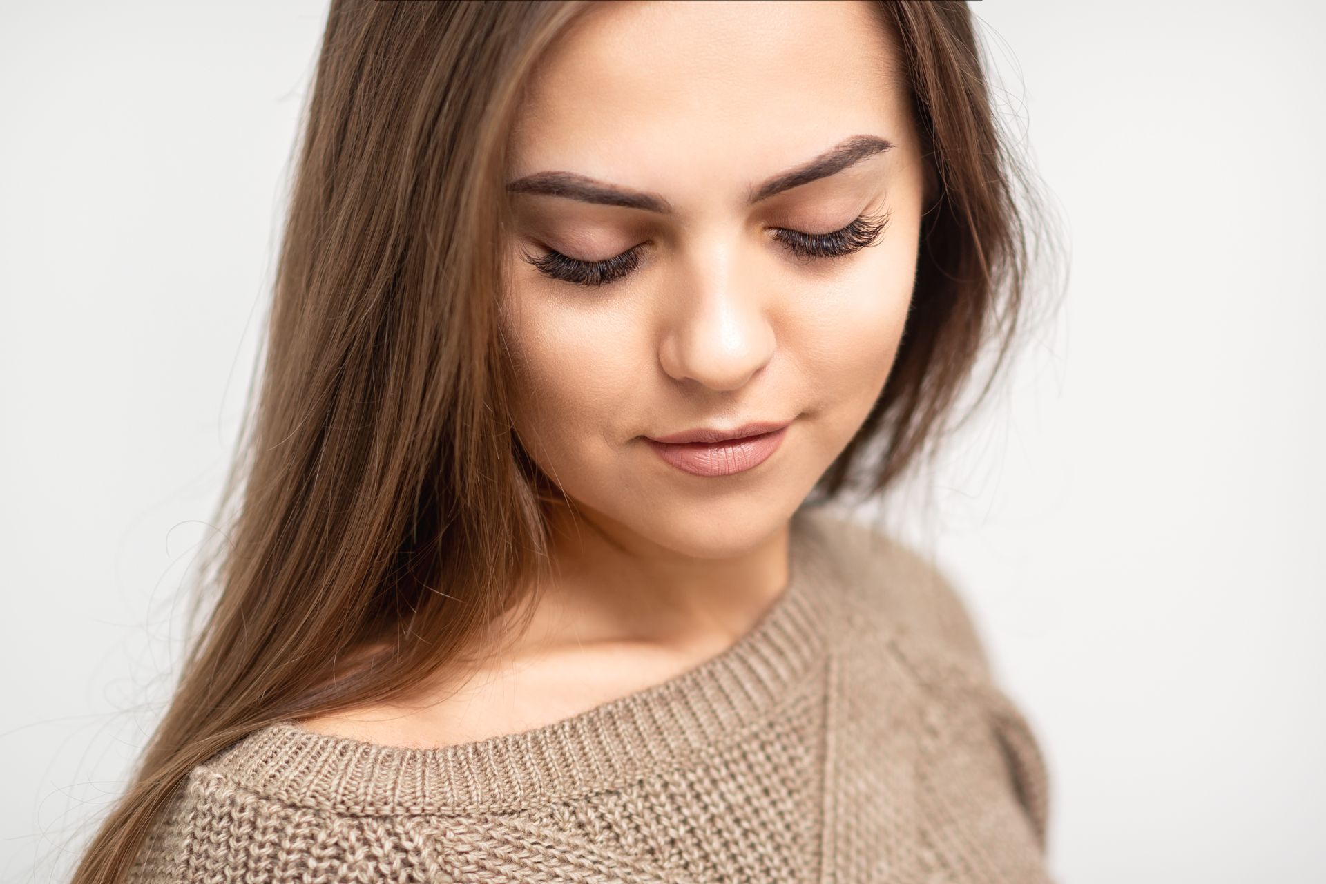 A close up of a woman wearing a sweater with her eyes closed.