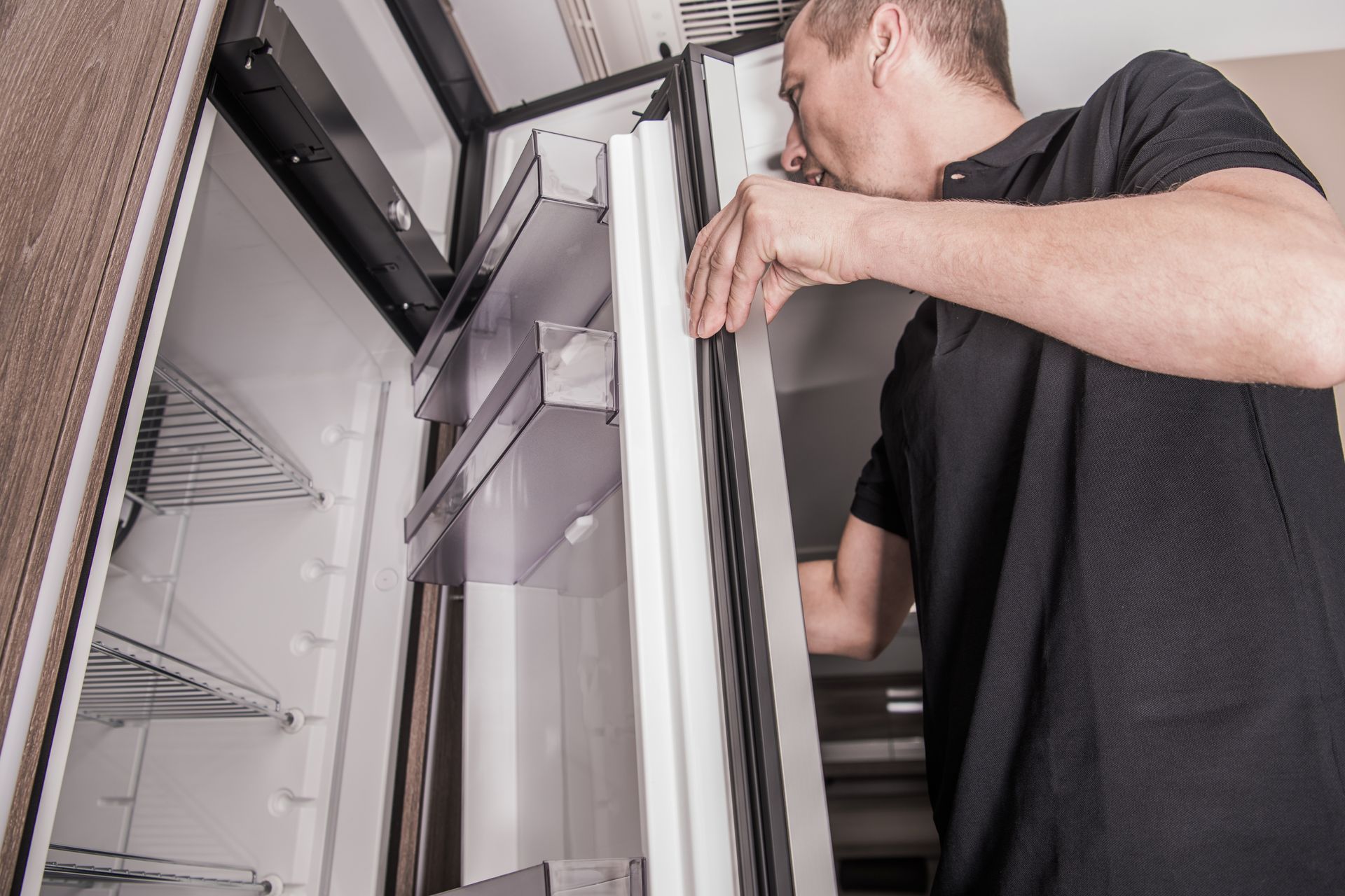 Person Adjusting a Refrigerator Door in a Kitchen — Dempsters Caravan & RV in Childers, QLD