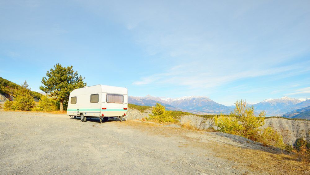 A White Rv is Parked in a Parking Lot With Mountains in the Background — Dempsters Caravan & RV in Hervey Bay, QLD