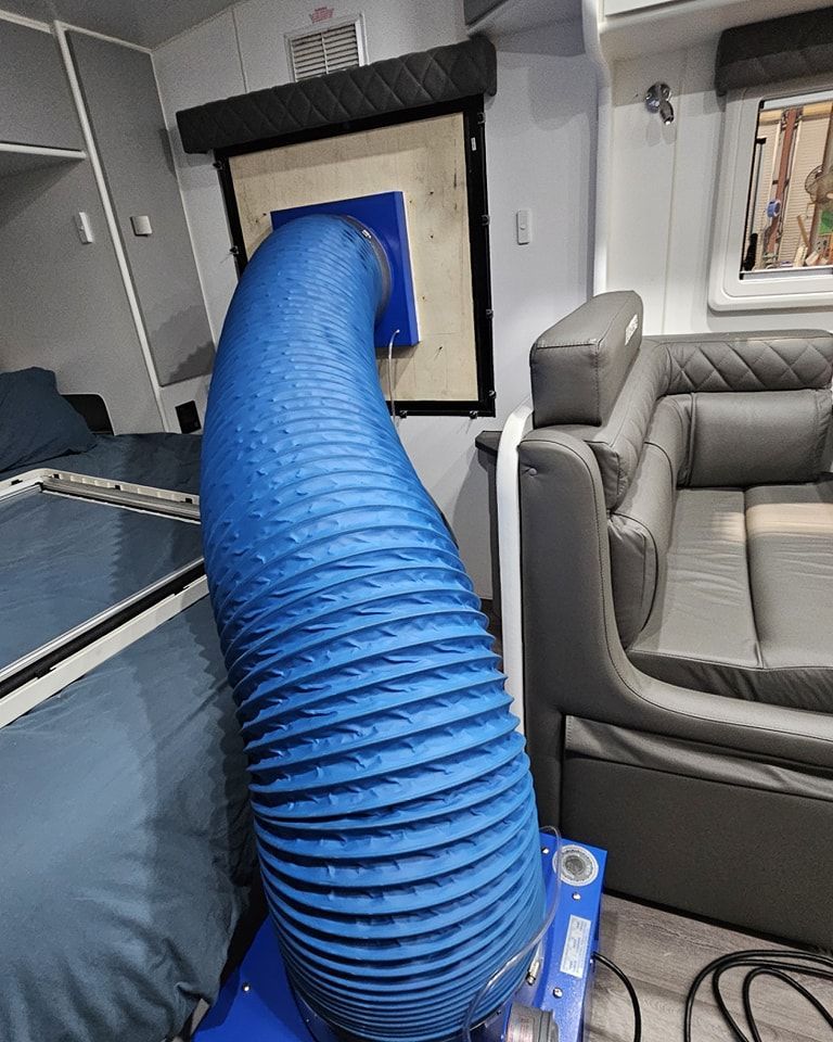 A Blue Hose is Connected to a Machine in a Living Room — Dempsters Caravan & RV in Thabeban, QLD