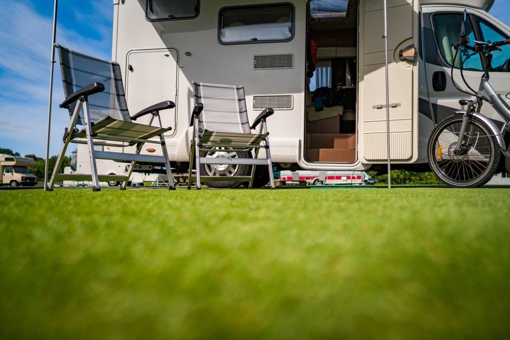 A Rv With Chairs and a Bicycle Parked on the Grass — Dempsters Caravan & RV in Rockhampton, QLD