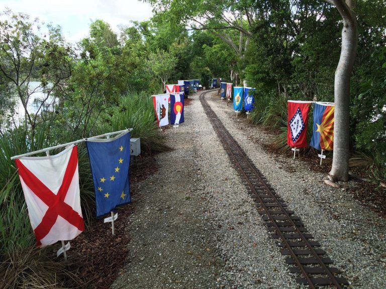 A row of flags are hanging on a railroad track