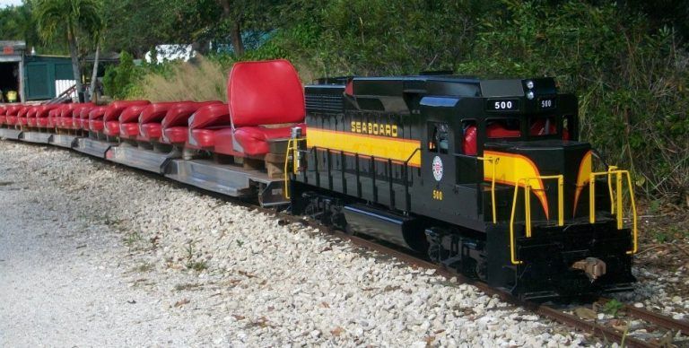 A black and yellow train with red seats on it is on the tracks.