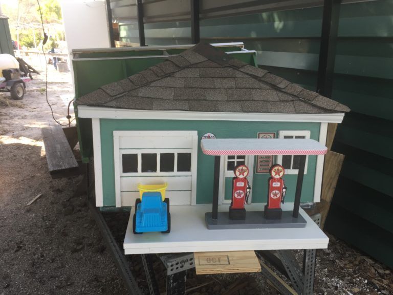 A miniature house with a garage and gas pumps