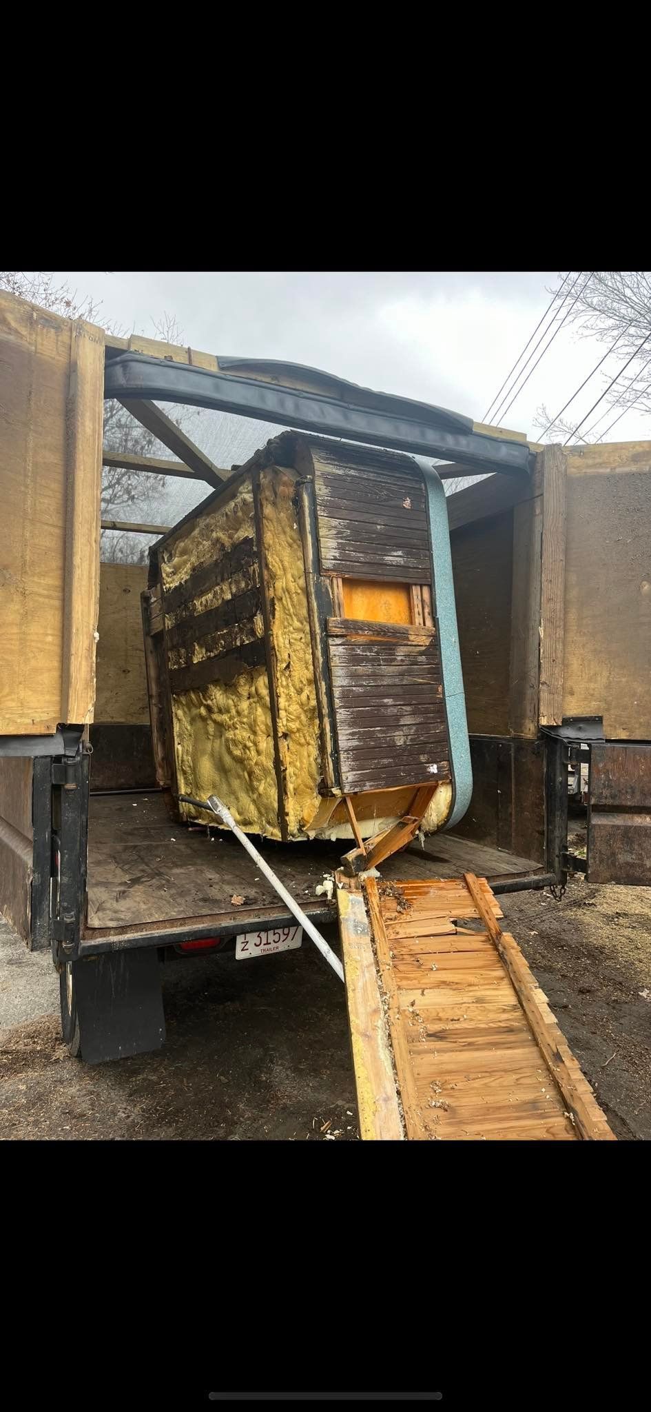 Woman in straw hat smiles, holding wine glass near a lake.