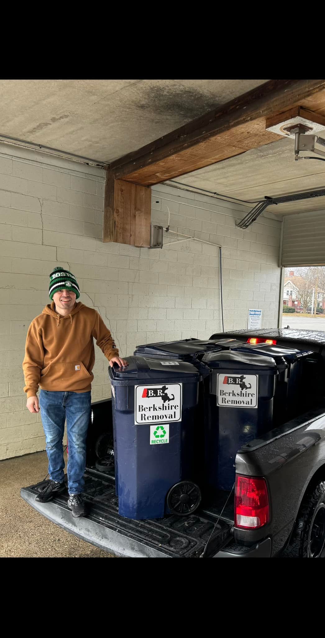 Woman in straw hat smiles, holding wine glass near a lake.