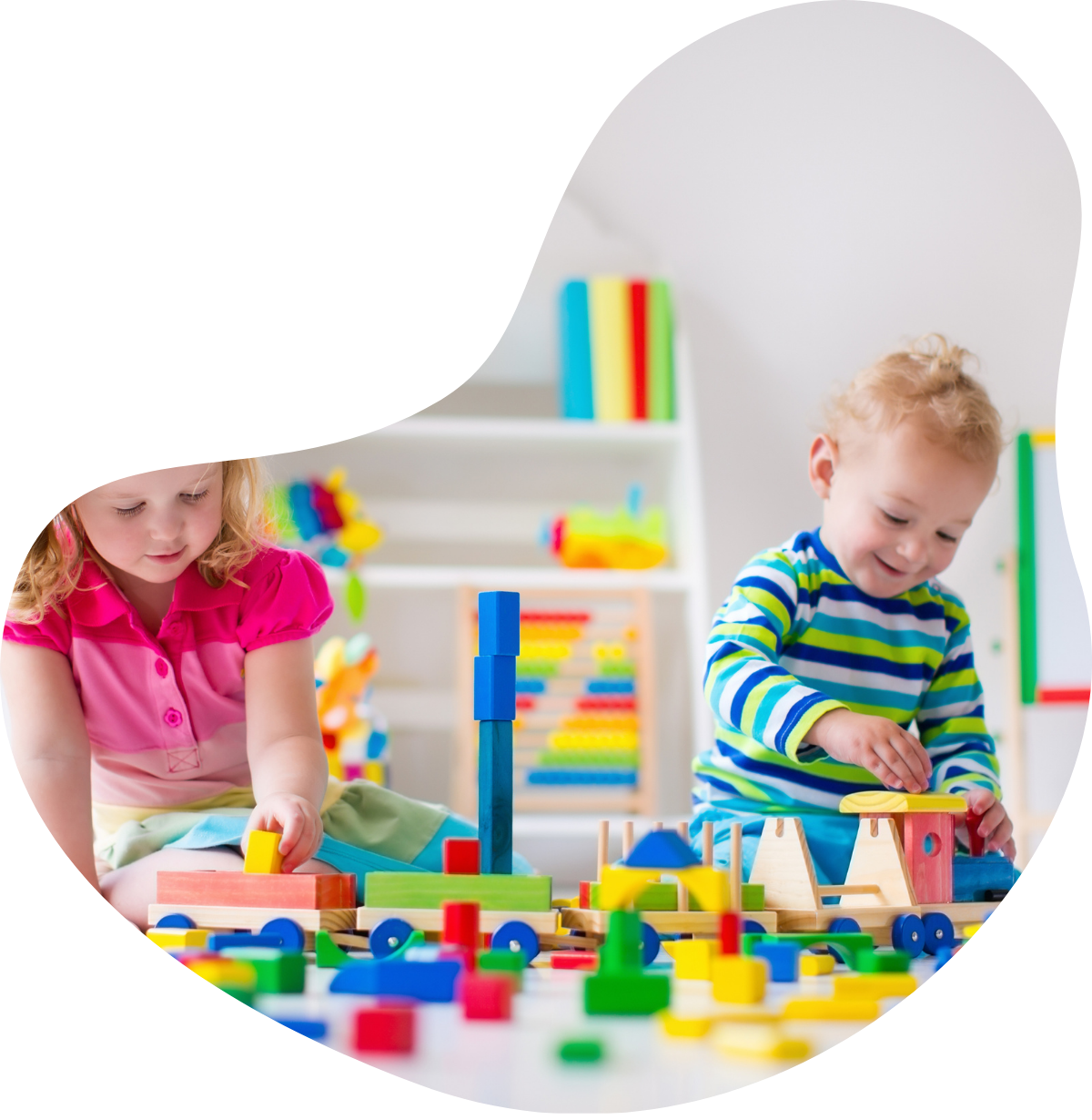 Two children playing with colorful wooden building blocks and train toys on the floor in a bright playroom.