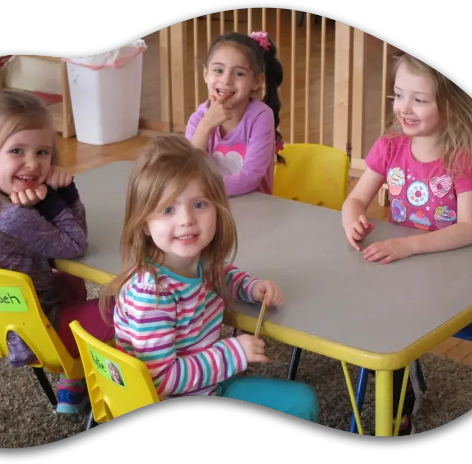 Four little girls are sitting at a table with one of them wearing a shirt that says pooh