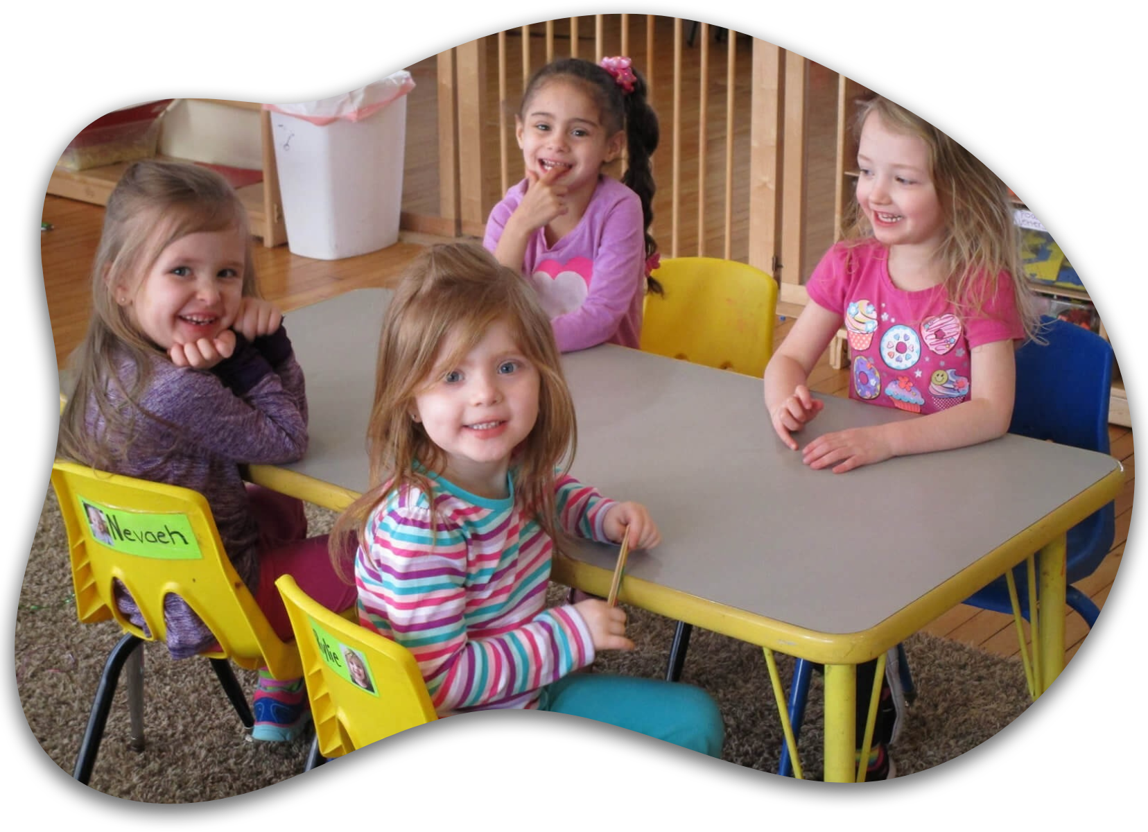 Four little girls are sitting at a table with one of them wearing a shirt that says pooh
