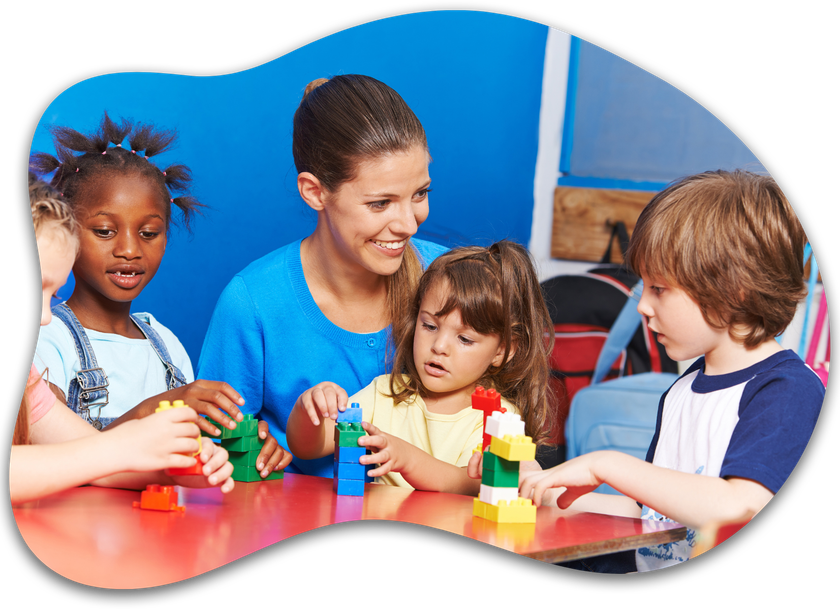 A woman is sitting at a table with children playing with blocks.