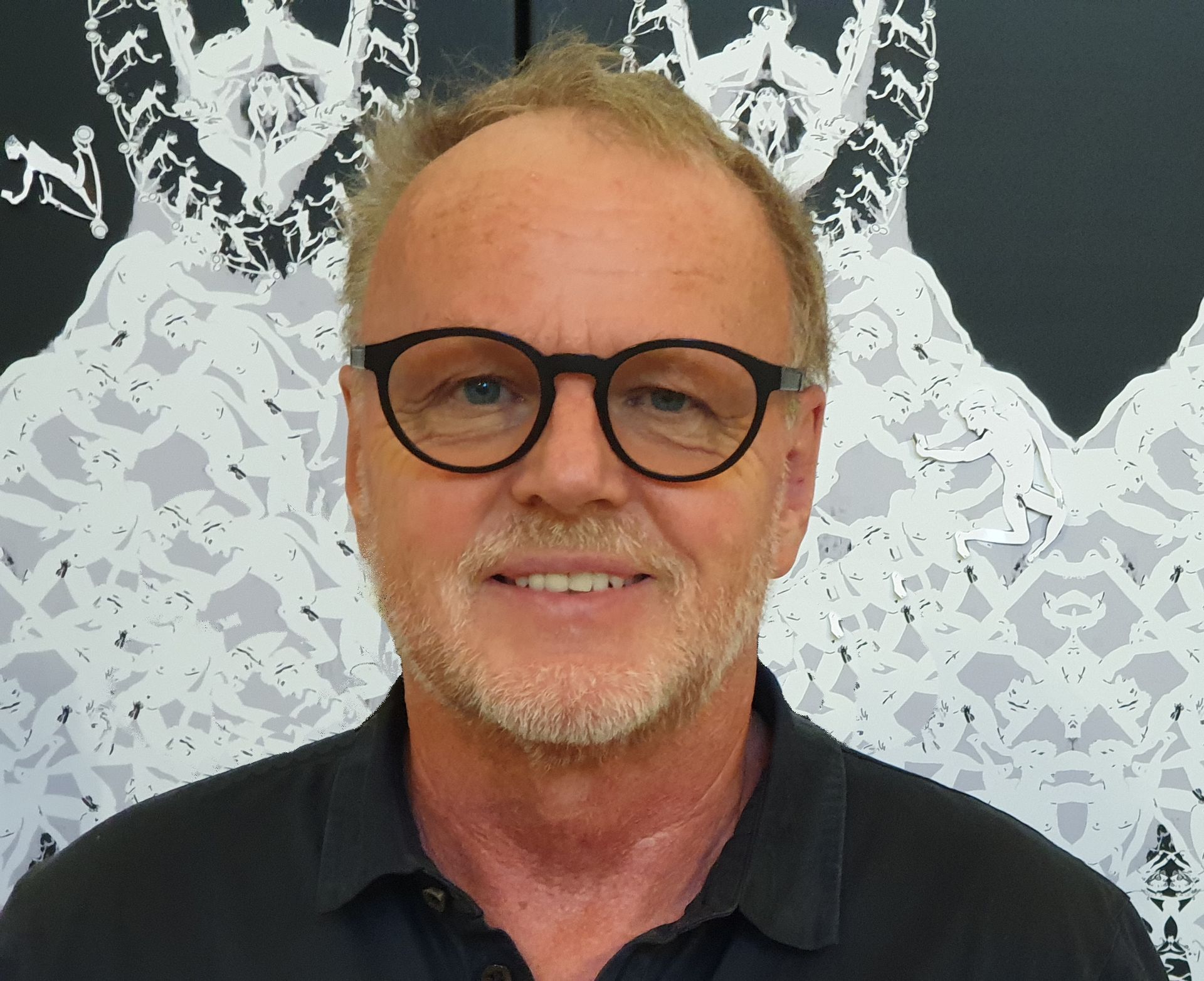 A man with glasses and a beard is smiling for the camera