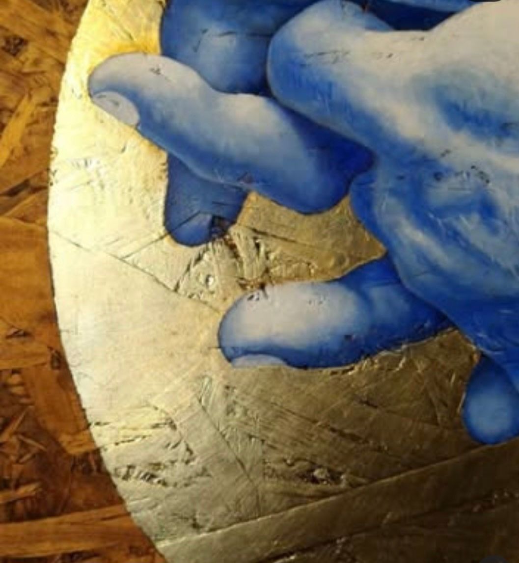 Blue hands reaching towards a gold circle on a wood surface.