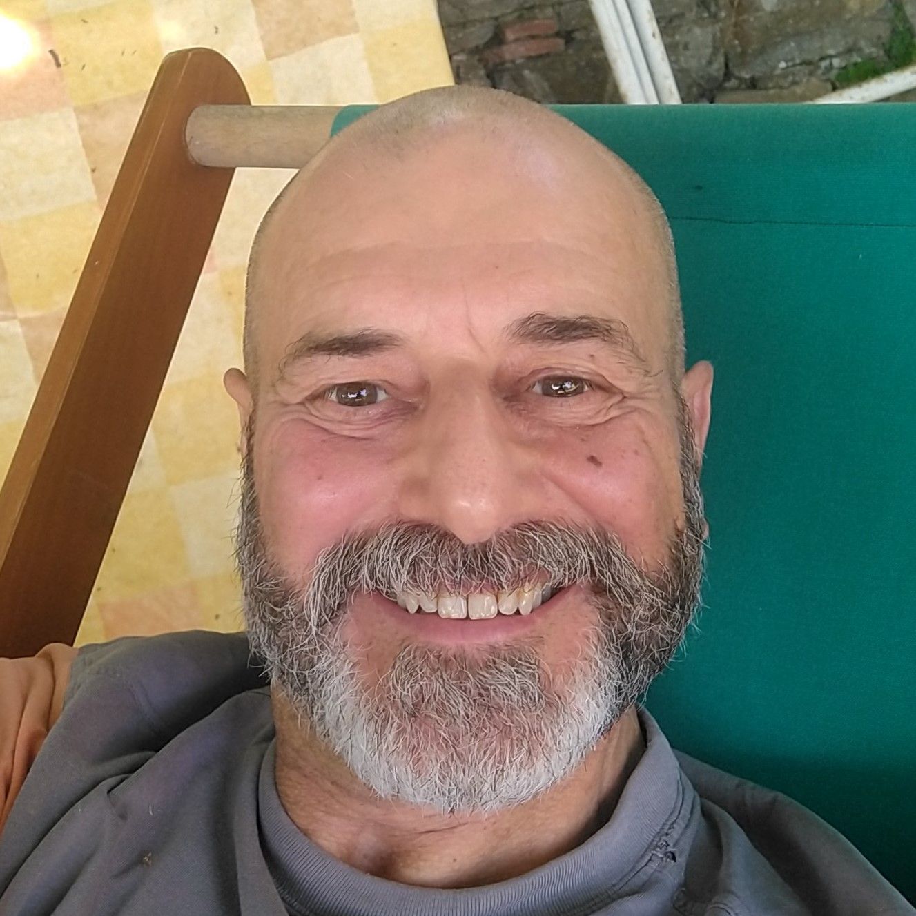 A man with a beard is smiling while sitting in a chair