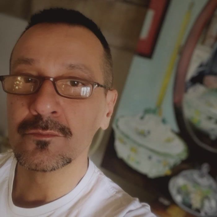 Aertist Franco Zucchella with glasses, mustache, and goatee, indoors, in a white shirt.