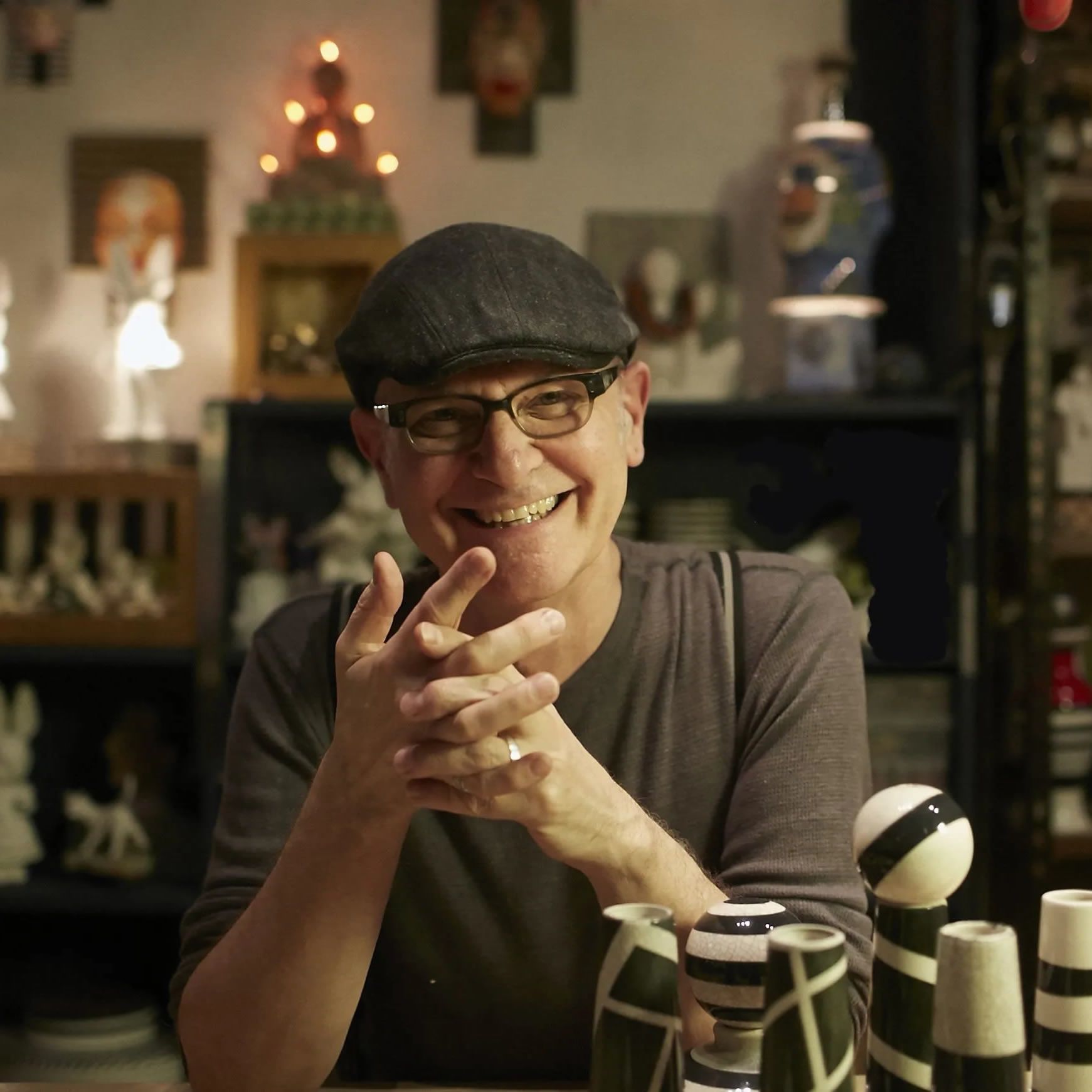A man wearing glasses and a hat is smiling while sitting at a table