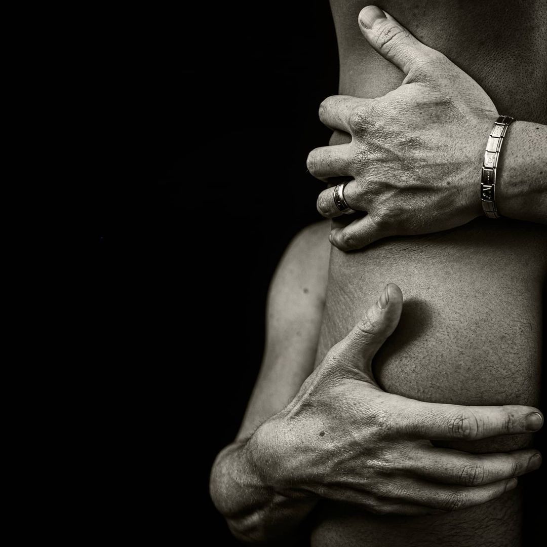 Two pairs of hands holding a person from behind; black and white photo.
