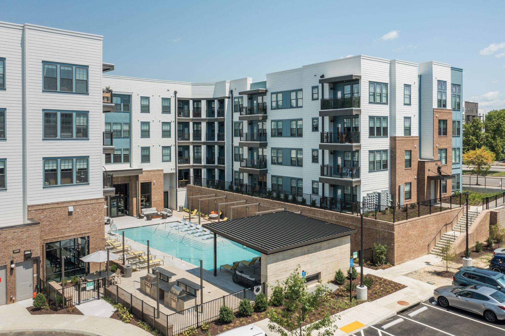 Drone view of the apartment building with a swimming pool in the middle of it.