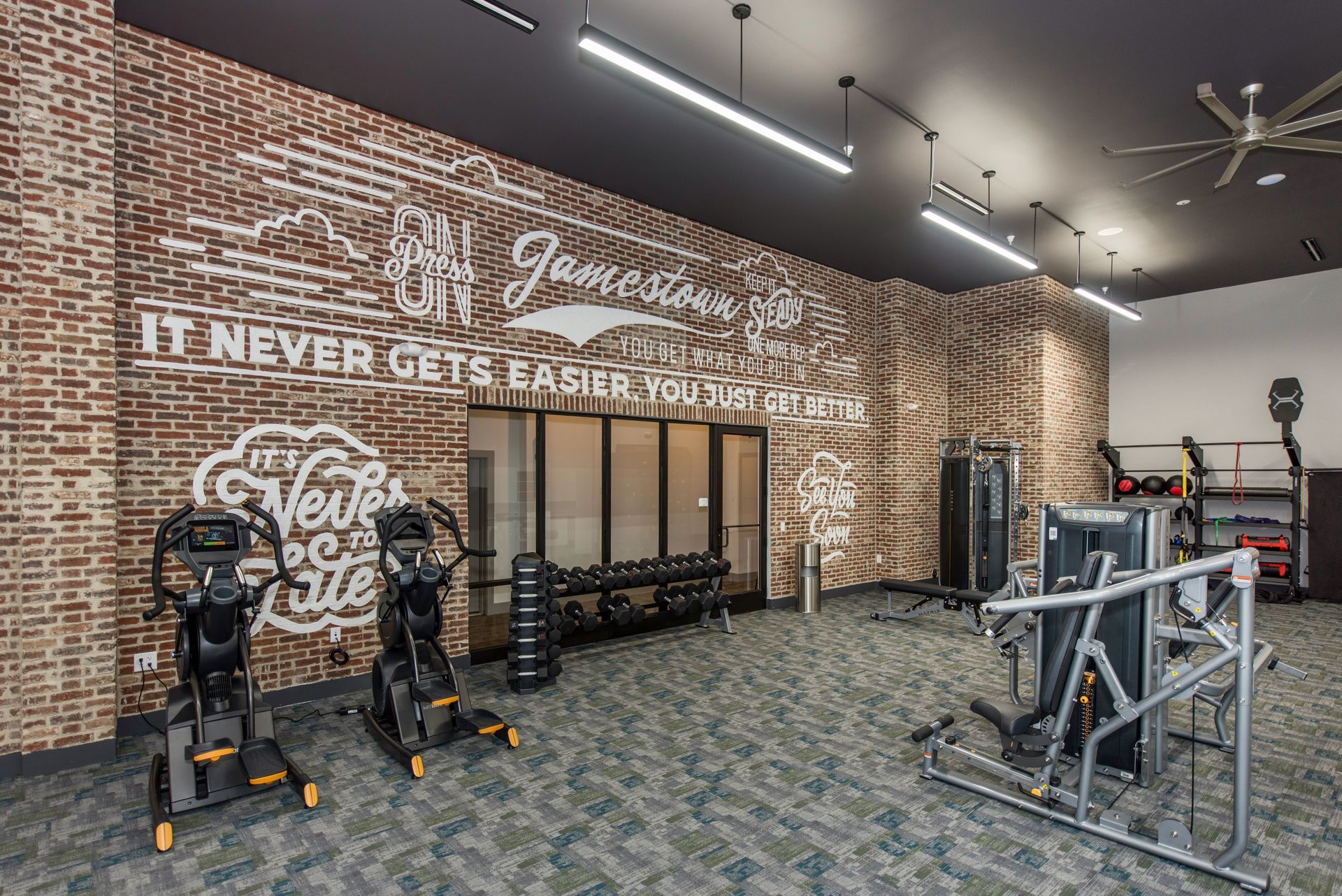 A gym with a brick wall and lots of exercise equipment.