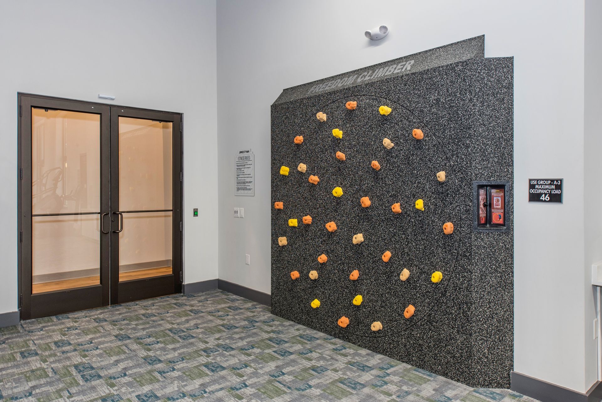There is a climbing wall in the hallway of a building.