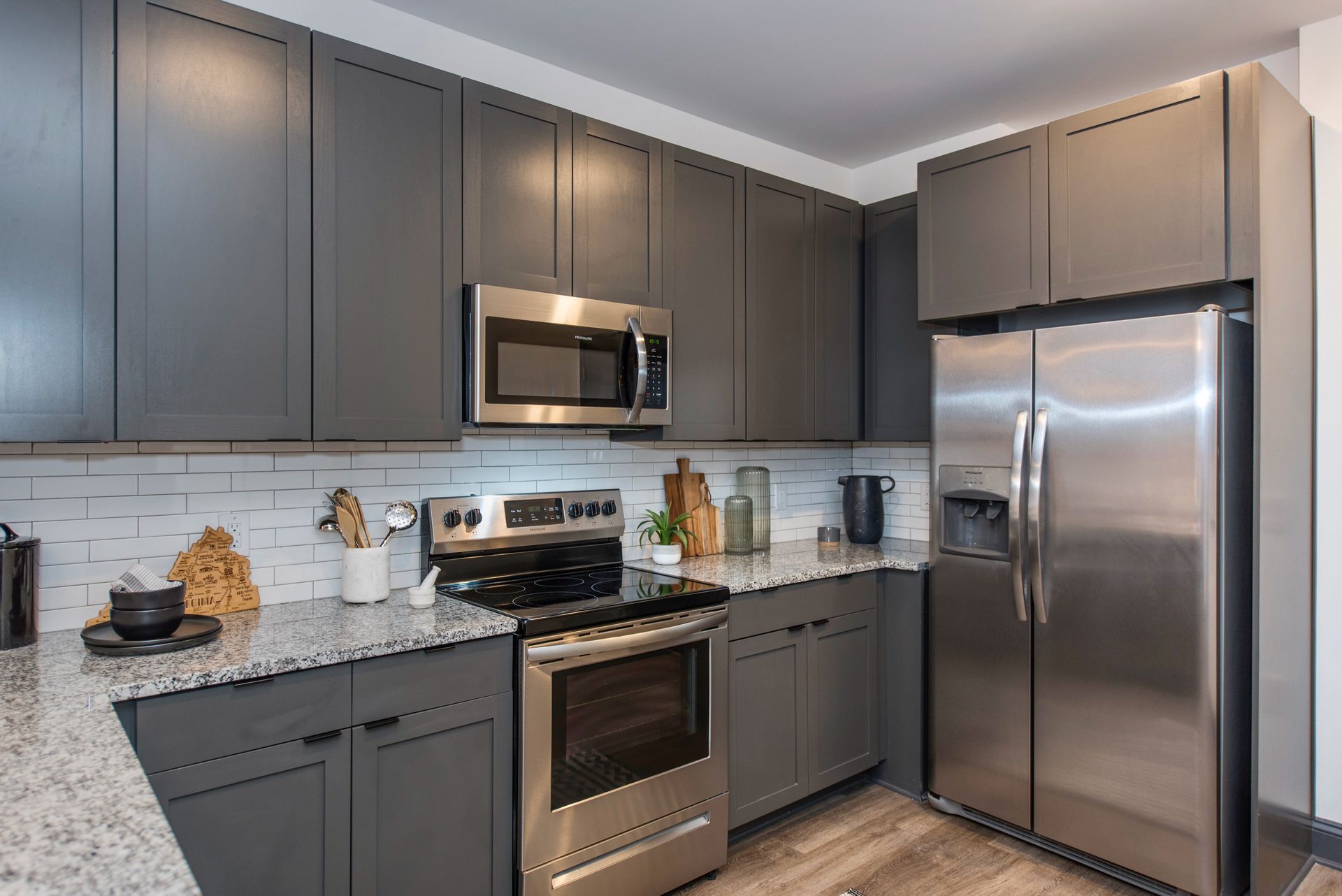 A kitchen with stainless steel appliances and gray cabinets.