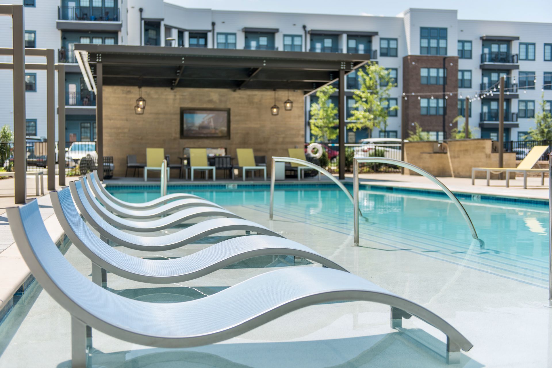 There is a large swimming pool in front of the apartment building.