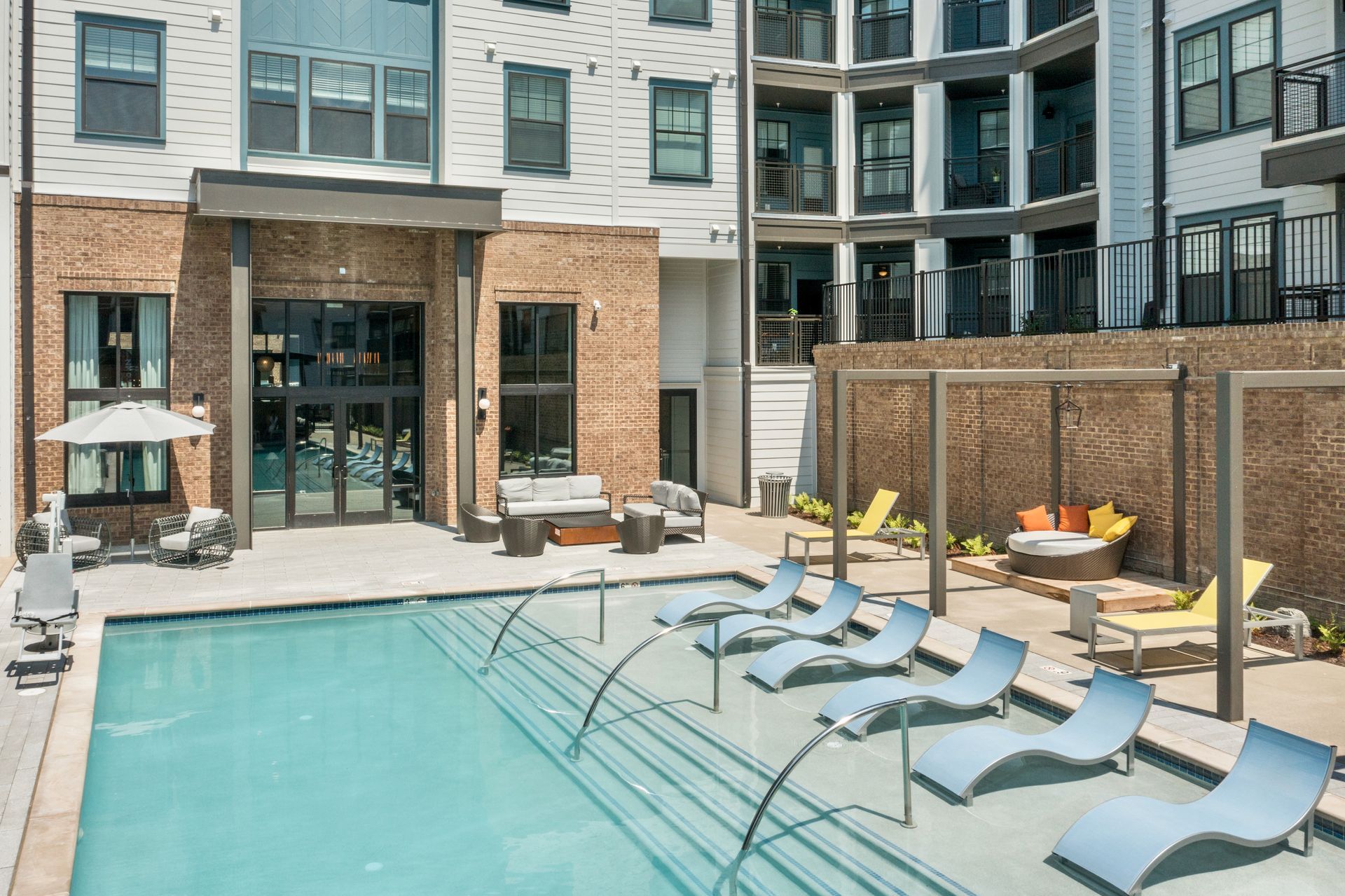A large swimming pool surrounded by lounge chairs in front of a building.