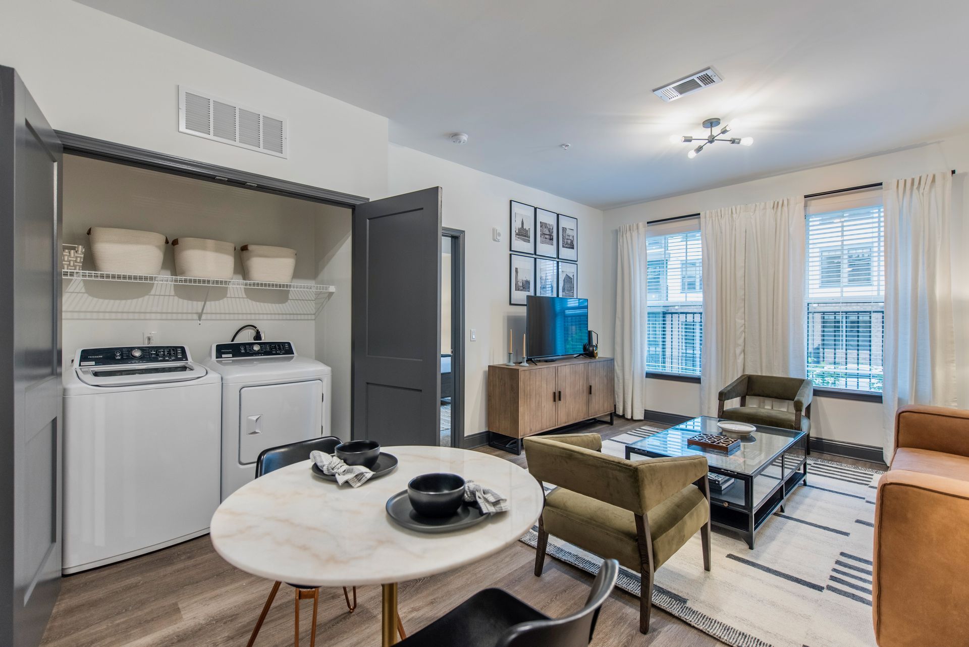 A living room with a washer and dryer and a dining table.