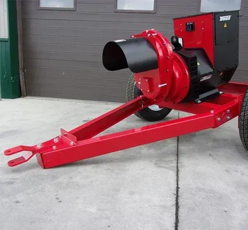 Red and black industrial blower on a trailer, likely for agricultural use, parked outside.