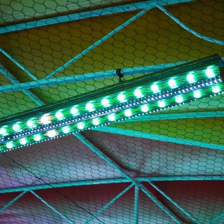 A green light is hanging from the ceiling of a building.
