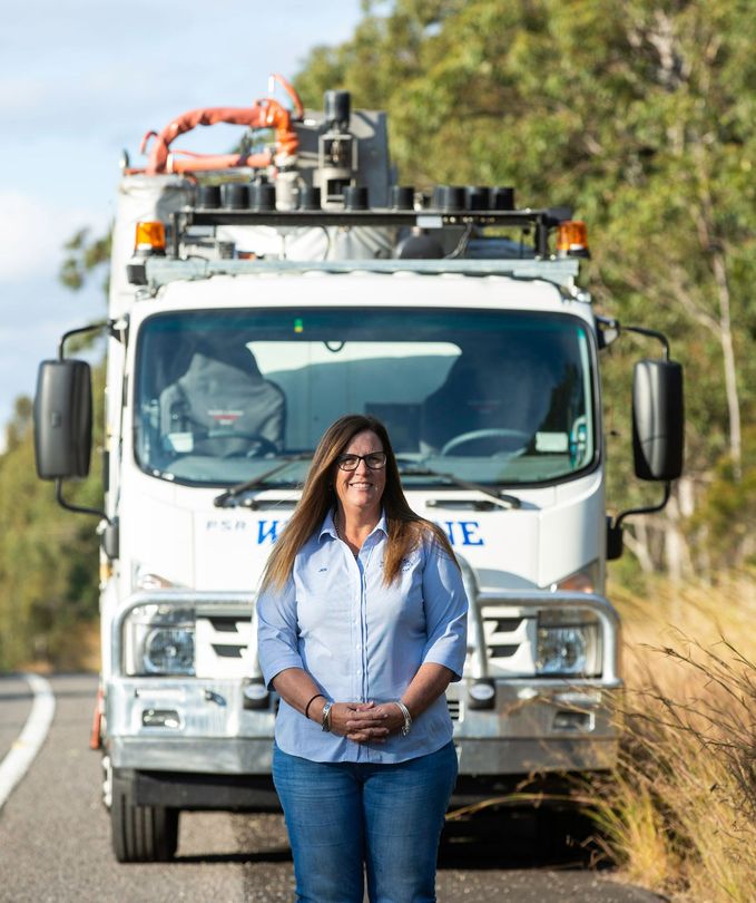 A woman is standing in front of a large white truck.