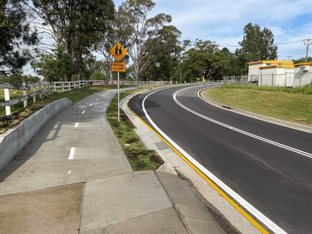 A curvy road with a yellow sign on the side of it