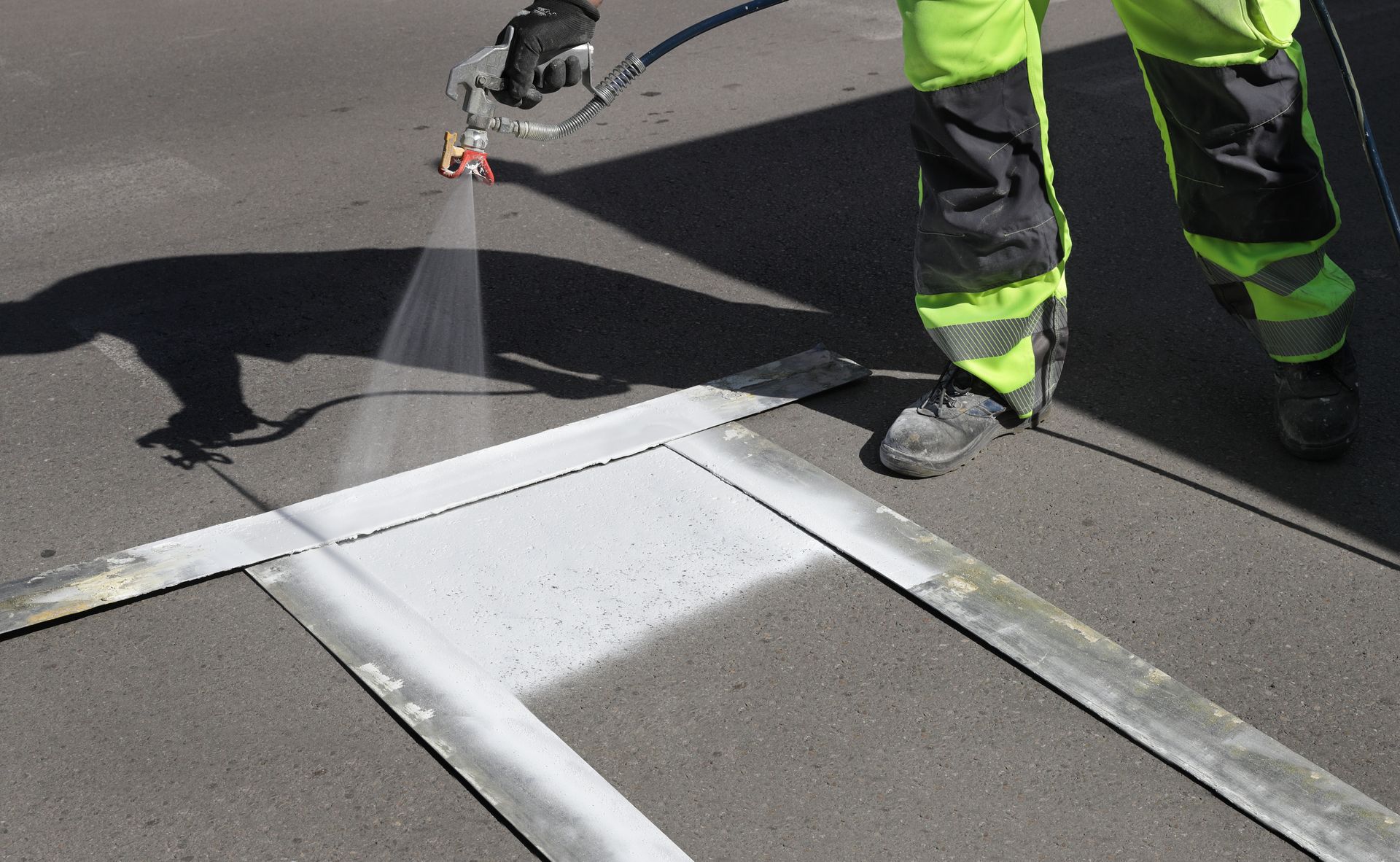 Worker spraying pedestrian crosswalk at a street.