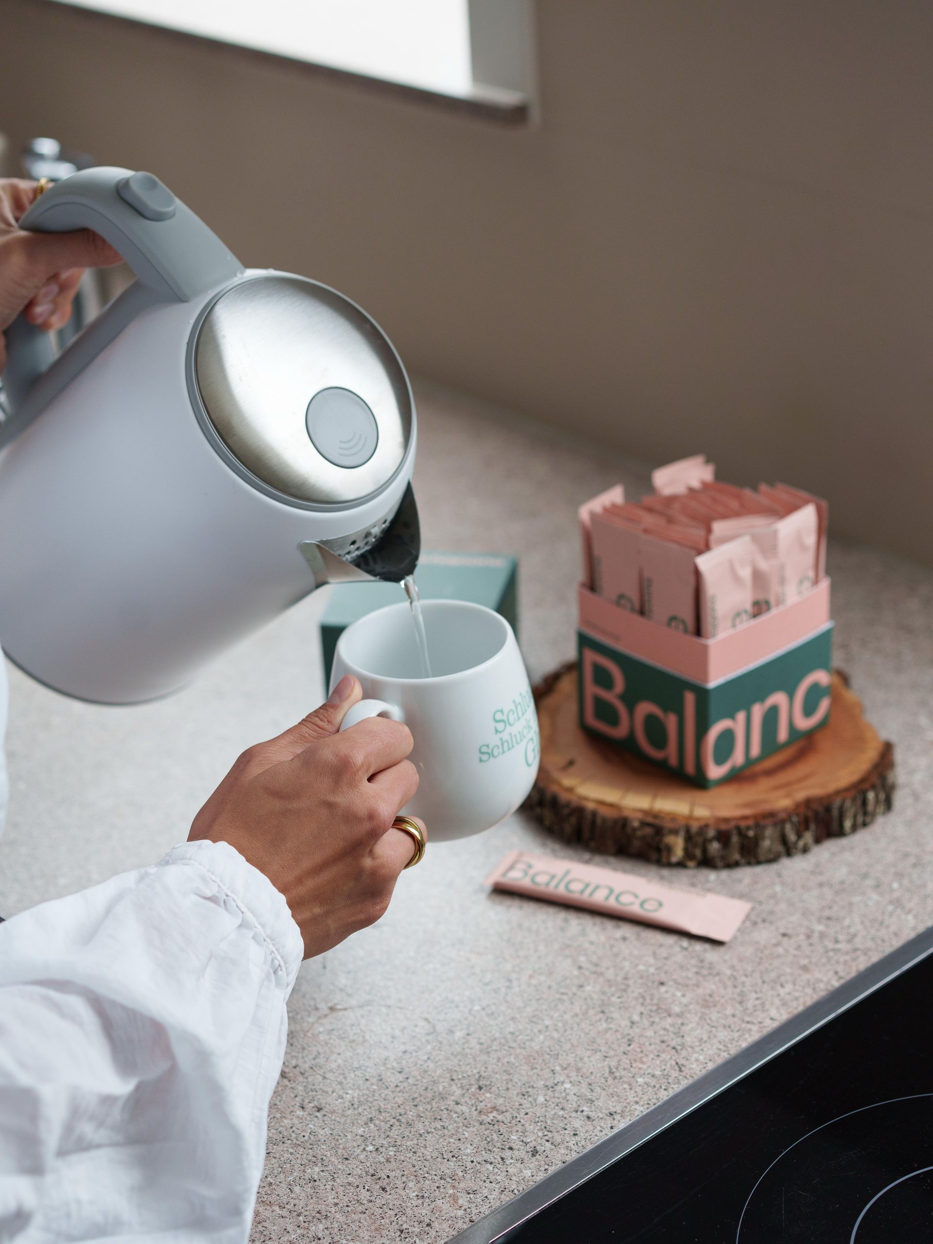 A person is pouring a cup of tea from a kettle