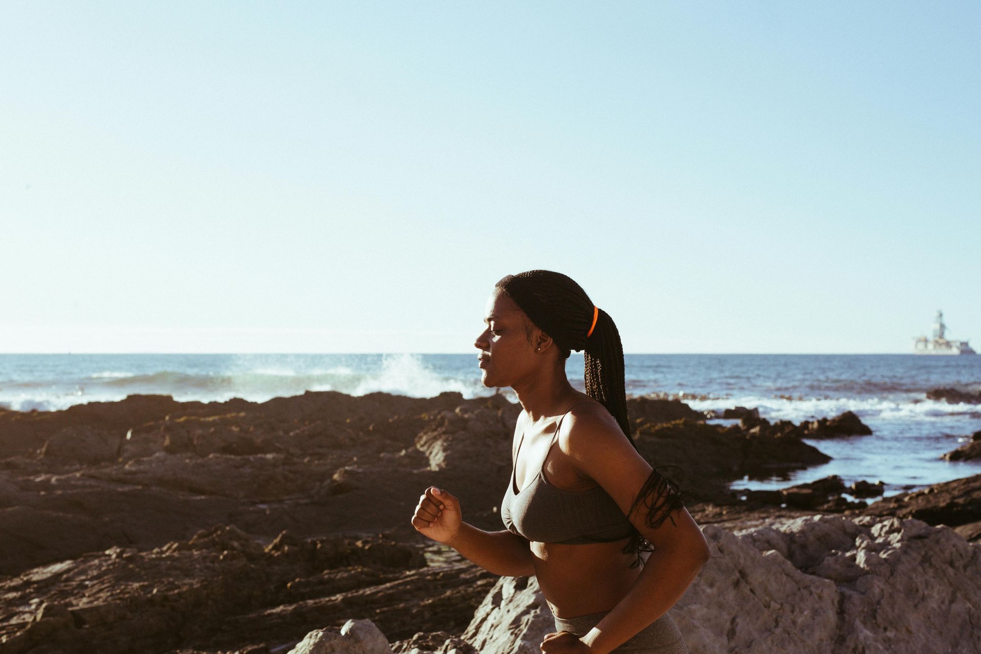A woman is running on a rocky beach near the ocean.