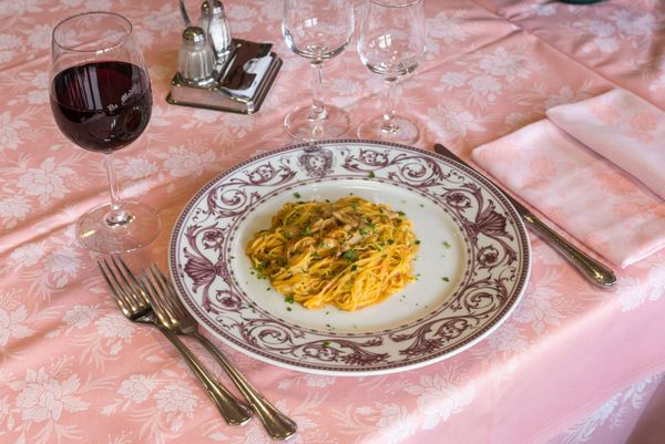 Zuppa in una ciotola rossa, guarnita con crostini e formaggio grattugiato su foglie di lattuga.