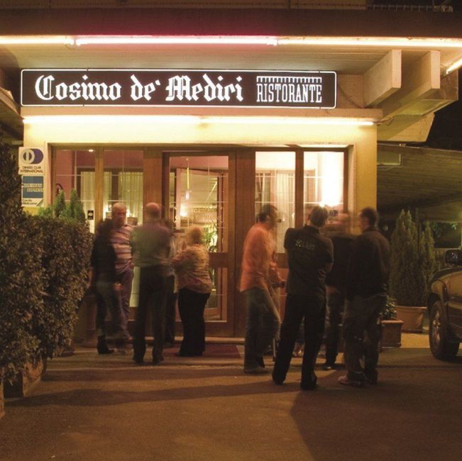 Di sera, sotto luci calde, le persone si sono radunate all'esterno del ristorante Cosimo d'Medici.