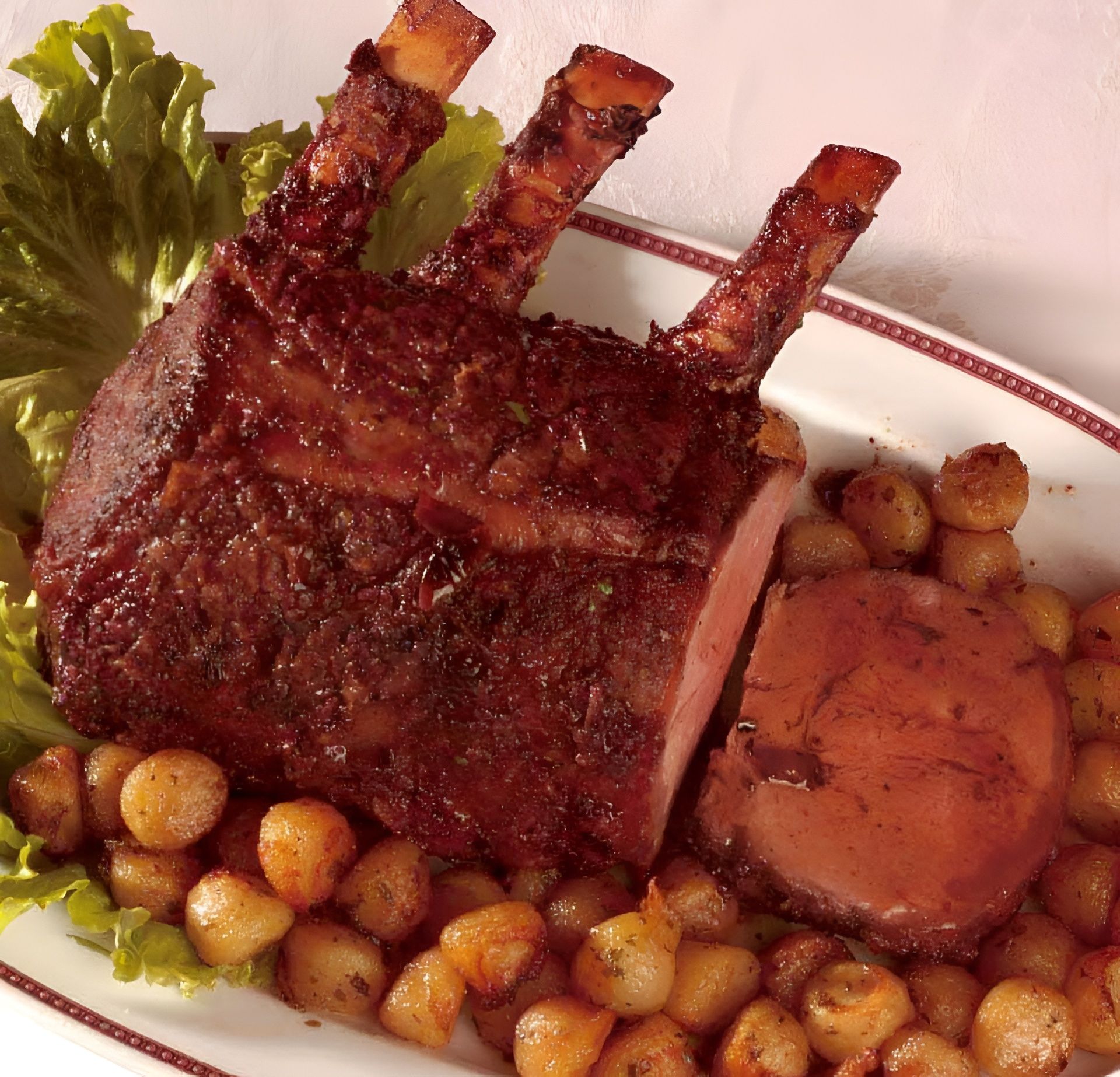 Carré di manzo arrosto con patate e verdure su un piatto bianco