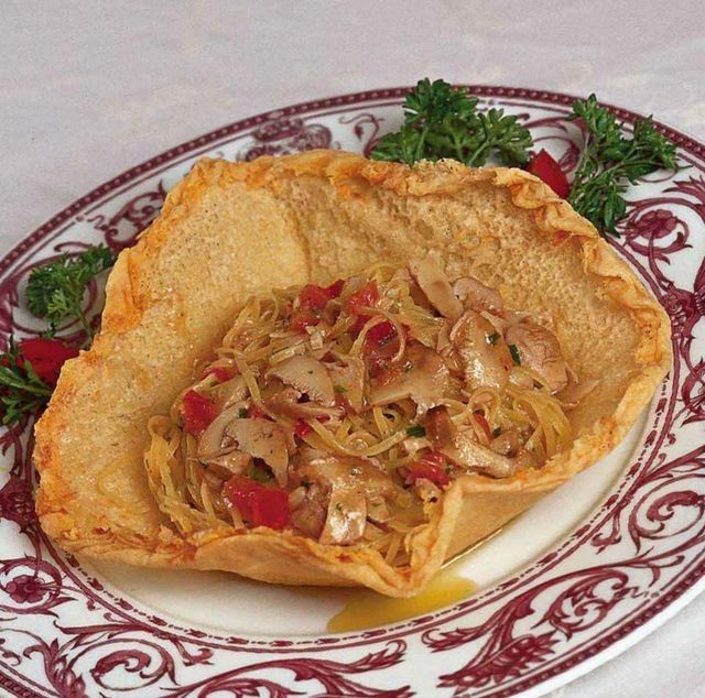 Ciotola di tortilla croccante ripiena di verdure saltate e guarnita con prezzemolo, servita su un piatto decorativo.