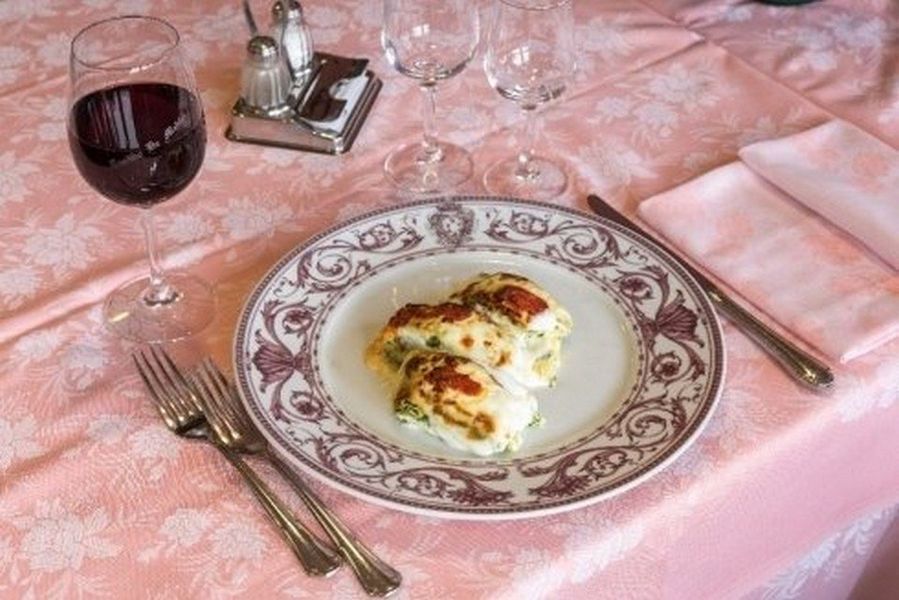 Elegante apparecchiatura della tavola con pietanze servite al momento, vino rosso e tovaglia rosa.