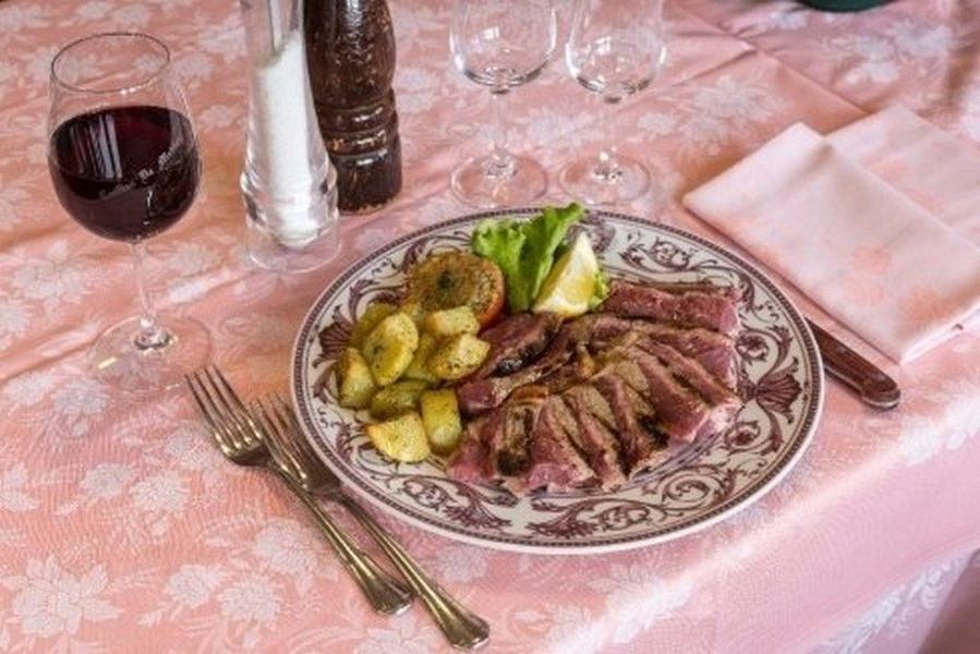 Tavolo da ristorante rustico con piatti e bicchieri in una luce calda, con uno sfondo di parete in legno.