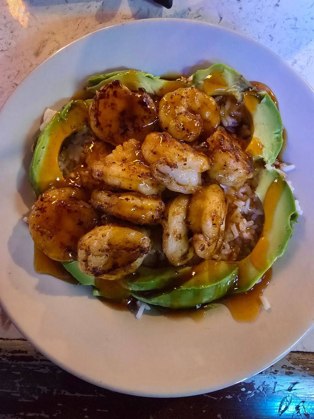 Shrimp and avocado dish with sauce on white plate.