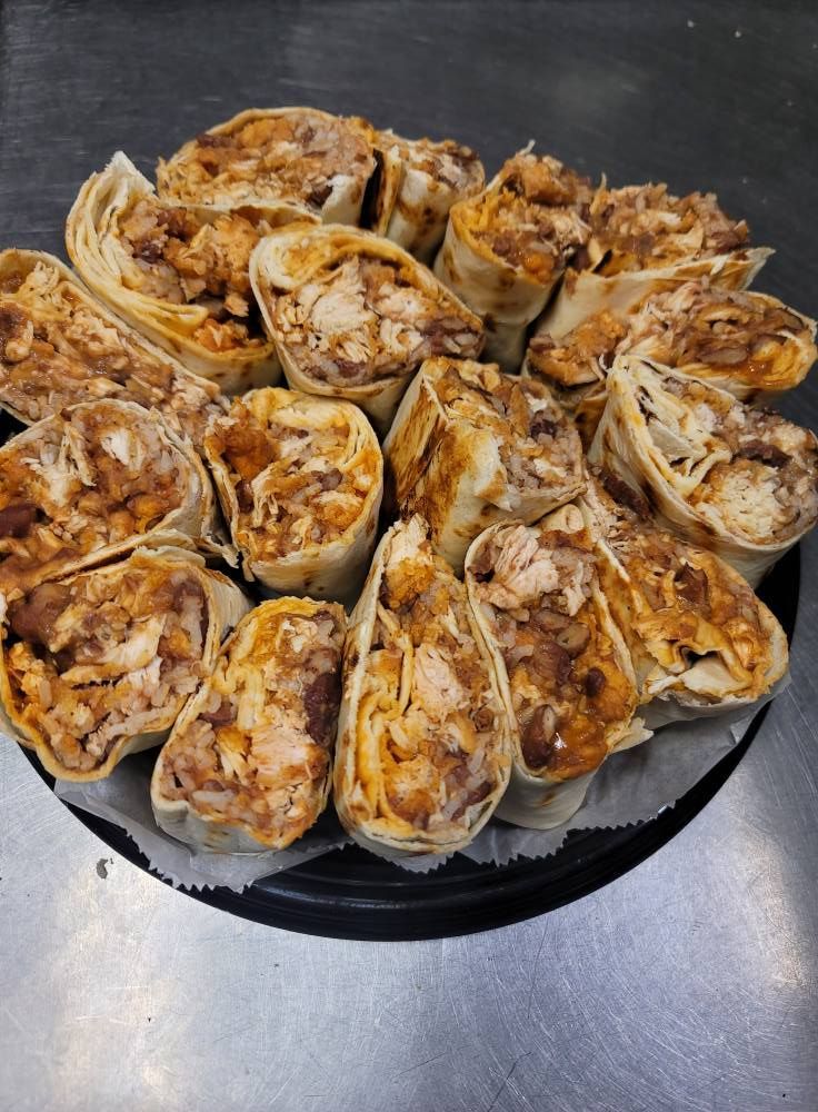 A platter of sliced shawarma wraps with visible filling of meat and sauce on a dark surface.