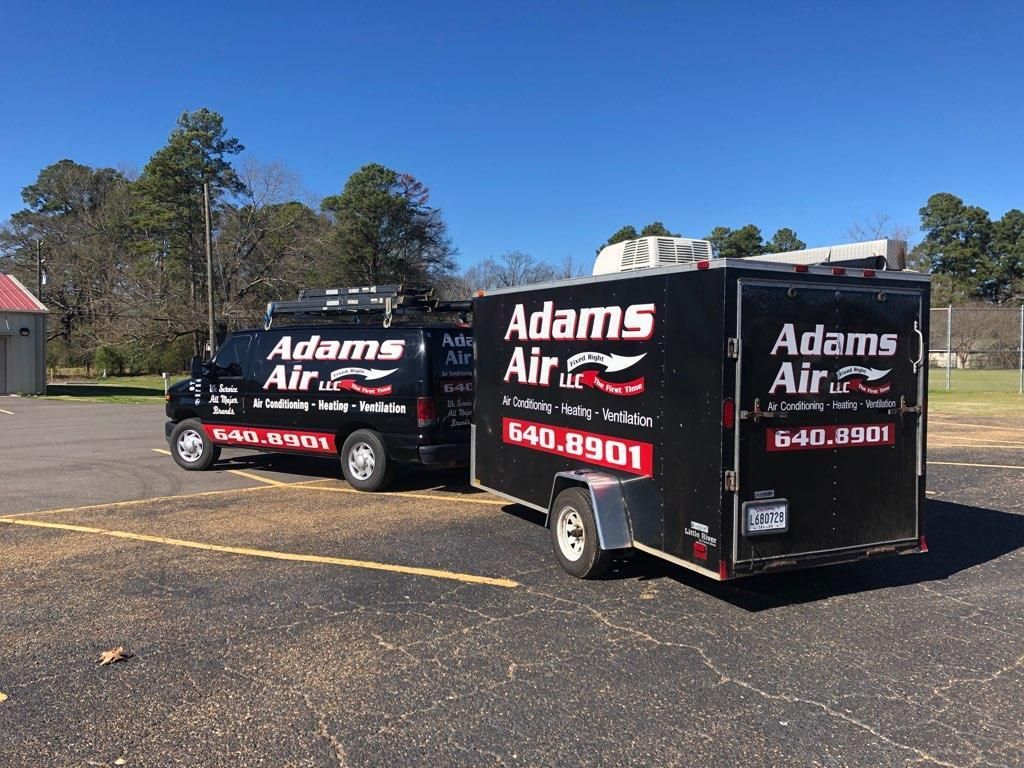 Two adams air trucks are parked next to each other in a parking lot.